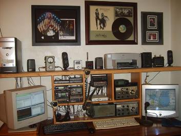 A multi-radio amateur station and BBS setup with computer, monitors, and several transceivers on a desk.